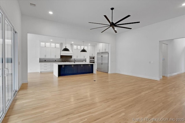 unfurnished living room with sink, light hardwood / wood-style flooring, and ceiling fan