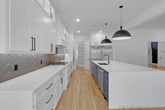 kitchen featuring white cabinetry, sink, hanging light fixtures, stainless steel appliances, and blue cabinetry