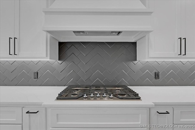 kitchen featuring tasteful backsplash, custom range hood, white cabinets, and stainless steel gas cooktop