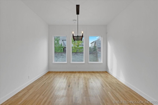 unfurnished dining area with light hardwood / wood-style flooring and a notable chandelier