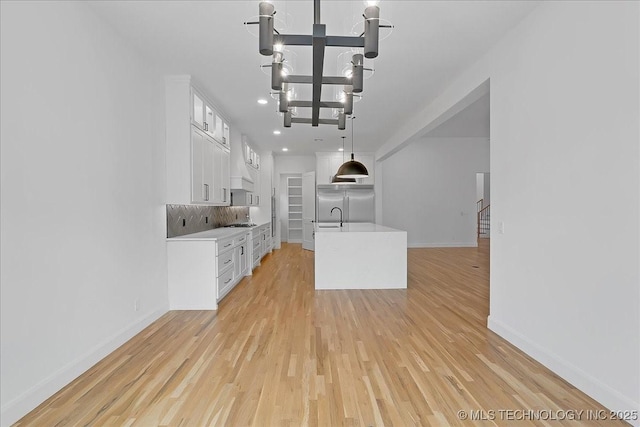 kitchen with gas cooktop, white cabinetry, backsplash, light hardwood / wood-style floors, and stainless steel built in fridge