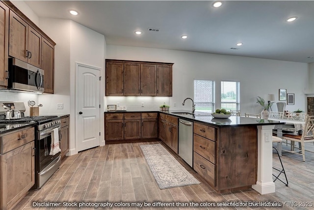 kitchen featuring a breakfast bar, sink, tasteful backsplash, appliances with stainless steel finishes, and kitchen peninsula