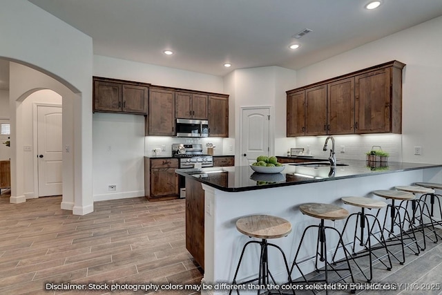 kitchen with sink, a breakfast bar, appliances with stainless steel finishes, tasteful backsplash, and kitchen peninsula