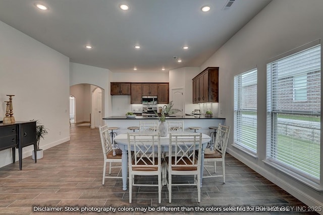 kitchen with stainless steel appliances, dark brown cabinetry, and a kitchen bar