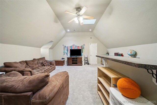 carpeted living room featuring ceiling fan and vaulted ceiling with skylight