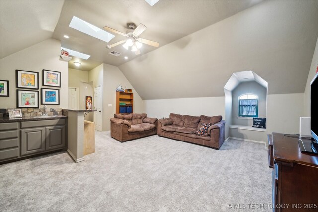 living room with lofted ceiling with skylight, sink, light colored carpet, and ceiling fan