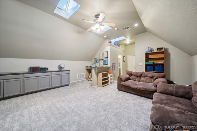 carpeted living room featuring ceiling fan and vaulted ceiling with skylight