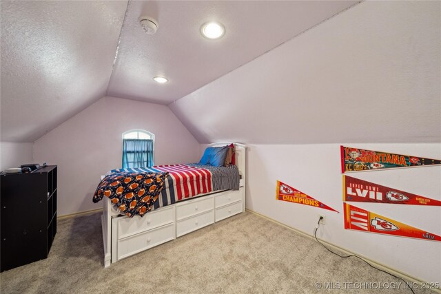 bedroom featuring vaulted ceiling, carpet flooring, and a textured ceiling