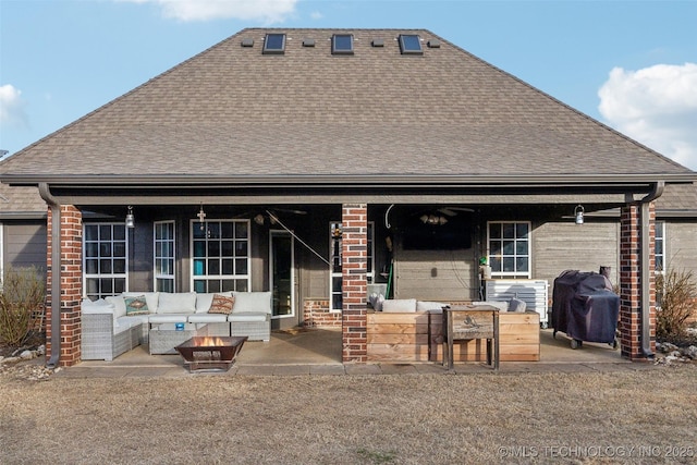 rear view of property featuring an outdoor living space with a fire pit and a patio