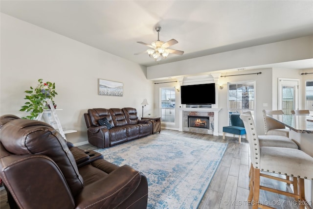 living room featuring a tiled fireplace, hardwood / wood-style floors, plenty of natural light, and ceiling fan