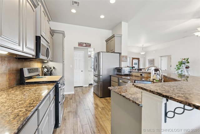 kitchen with sink, gray cabinetry, light wood-type flooring, stainless steel appliances, and decorative backsplash