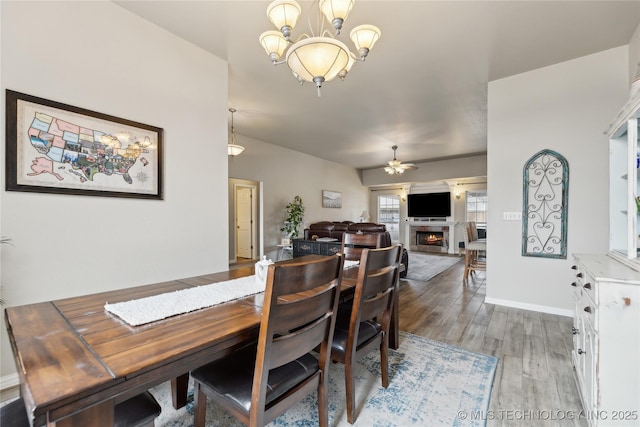 dining space with hardwood / wood-style flooring and ceiling fan with notable chandelier