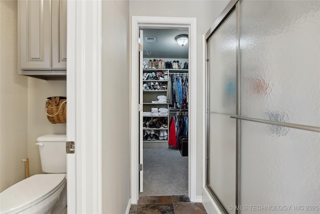 bathroom with toilet and a shower with shower door