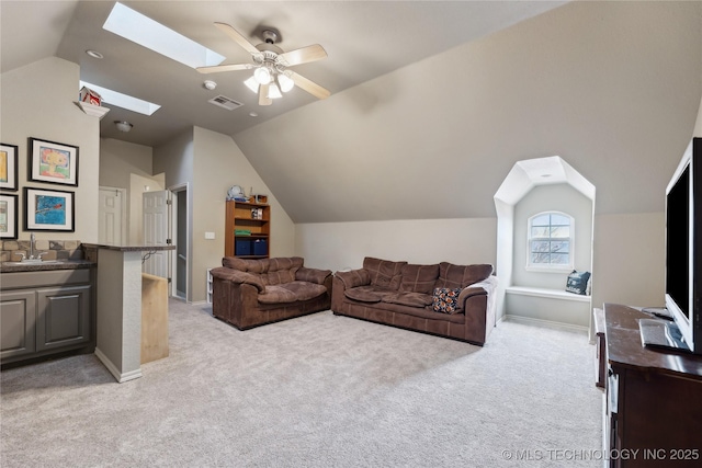 carpeted living room featuring ceiling fan, lofted ceiling with skylight, and sink