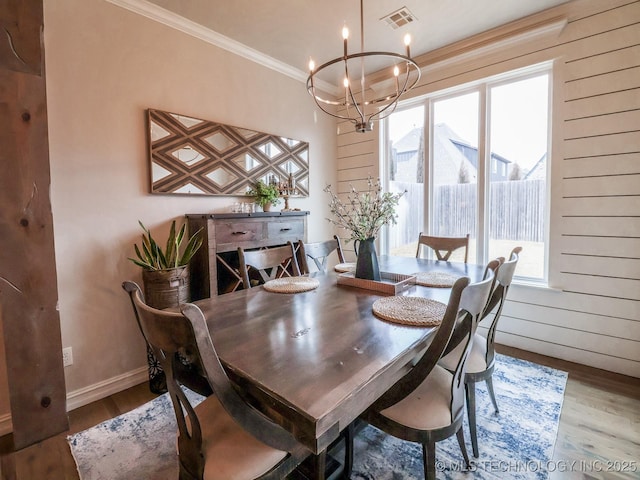 dining space featuring crown molding, a wealth of natural light, light wood-type flooring, and a notable chandelier