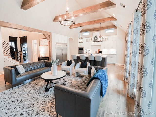 living room with beamed ceiling, high vaulted ceiling, light wood-type flooring, and a notable chandelier