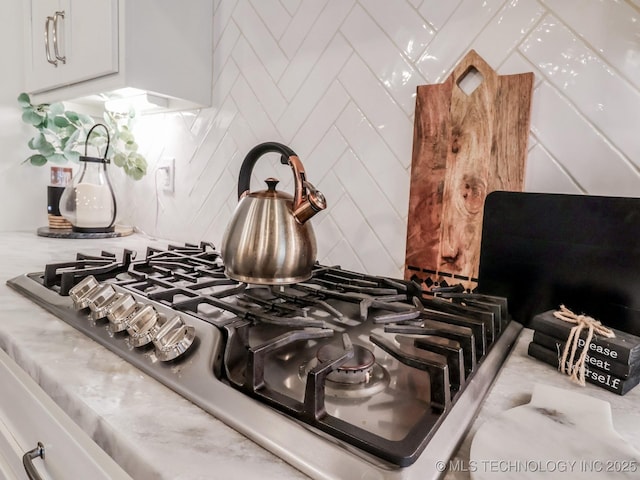 interior details with backsplash, stainless steel gas cooktop, and white cabinets