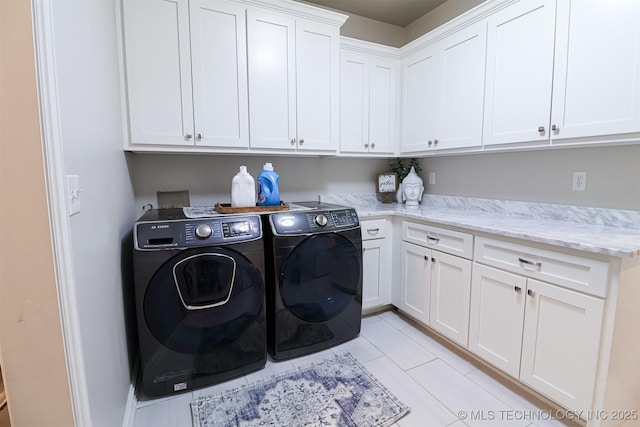 clothes washing area with washer and clothes dryer and cabinets