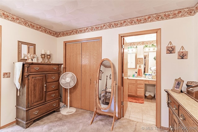 bedroom with connected bathroom, built in desk, and light tile patterned flooring