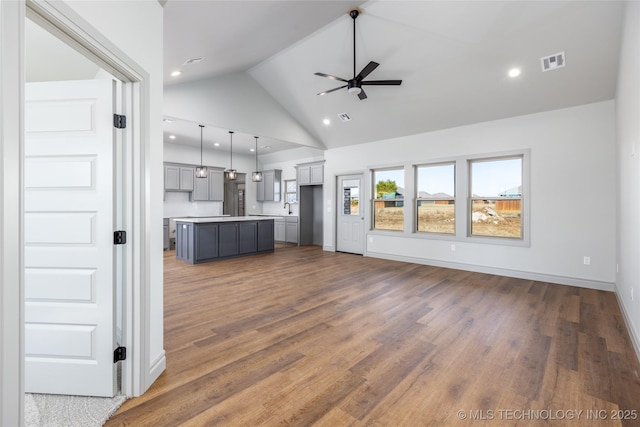 unfurnished living room with dark hardwood / wood-style flooring, high vaulted ceiling, and ceiling fan