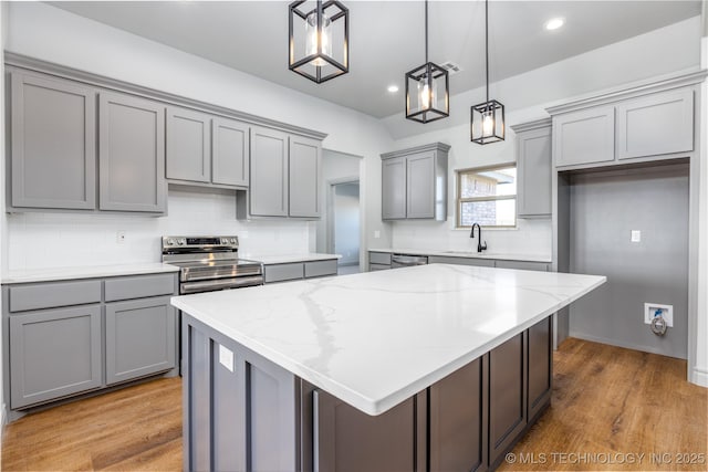 kitchen with a kitchen island, pendant lighting, gray cabinetry, light stone counters, and electric stove