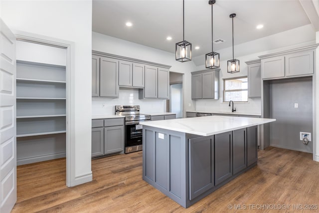 kitchen featuring pendant lighting, stainless steel range with electric stovetop, gray cabinets, and a kitchen island