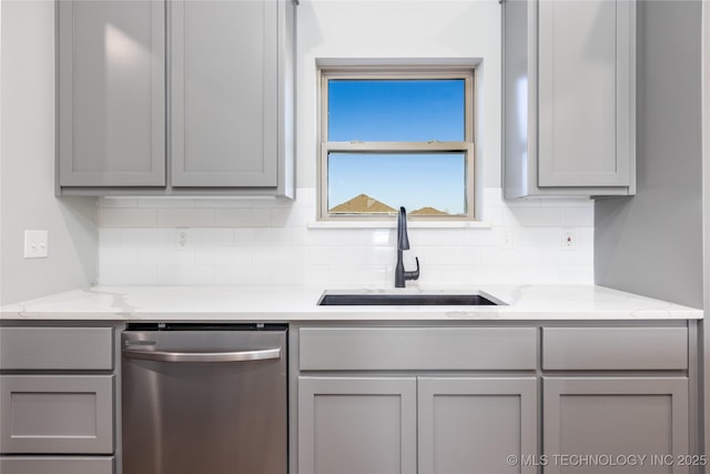 kitchen with light stone counters, dishwasher, sink, and gray cabinetry