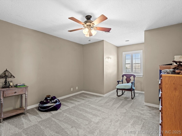 sitting room with ceiling fan, light colored carpet, and a textured ceiling