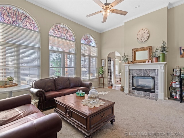 living room featuring light carpet, crown molding, a fireplace, and ceiling fan