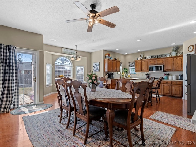 dining space with wood-type flooring, a textured ceiling, and a wealth of natural light