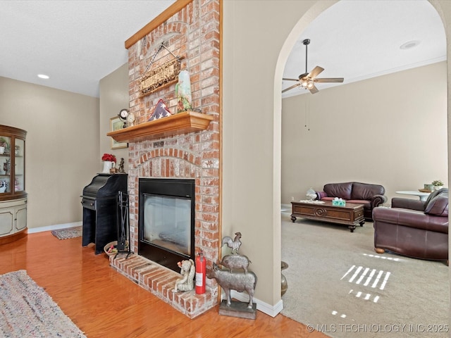 living room with ceiling fan, a textured ceiling, and a fireplace