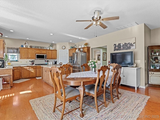 dining room with ceiling fan, a textured ceiling, and light wood-type flooring