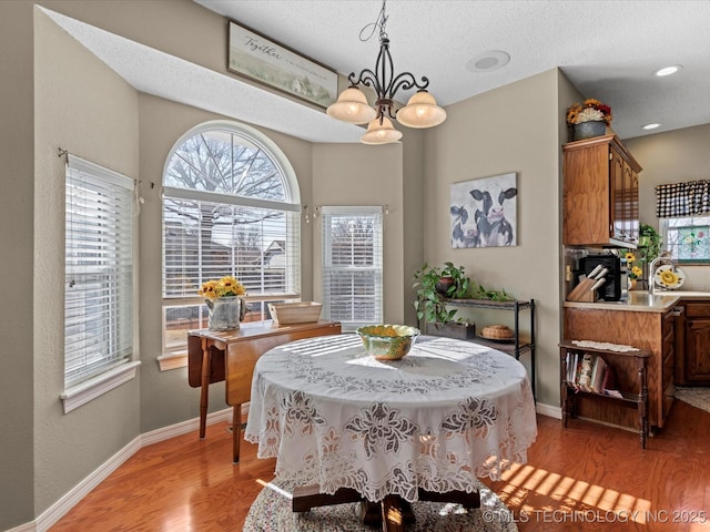 dining room with a healthy amount of sunlight, a chandelier, sink, and light hardwood / wood-style flooring