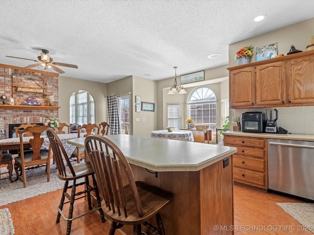 kitchen featuring a kitchen island, a breakfast bar, pendant lighting, dishwasher, and backsplash