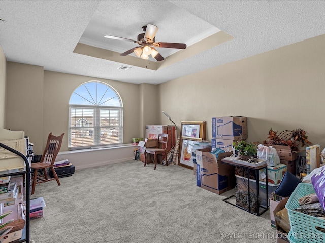 interior space with ceiling fan, crown molding, a raised ceiling, and a textured ceiling