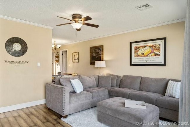 living room featuring crown molding, ceiling fan with notable chandelier, hardwood / wood-style floors, and a textured ceiling