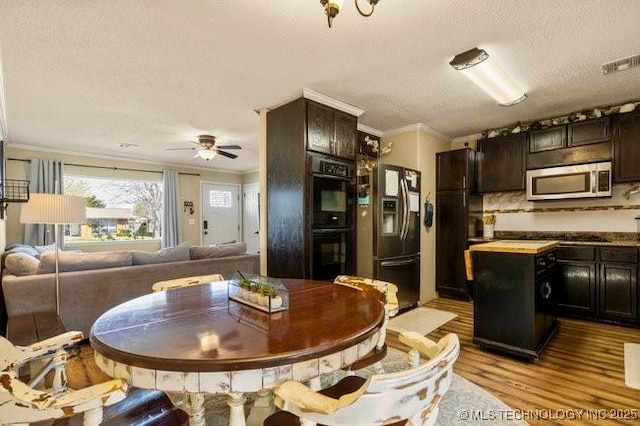 kitchen featuring crown molding, appliances with stainless steel finishes, dark brown cabinets, and light hardwood / wood-style flooring