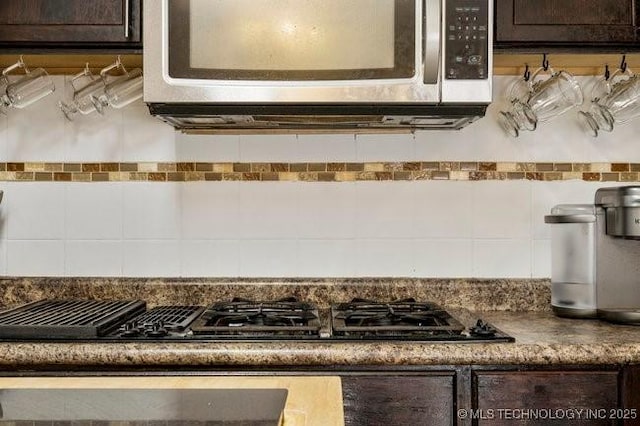 room details with dark brown cabinetry, black gas stovetop, and decorative backsplash