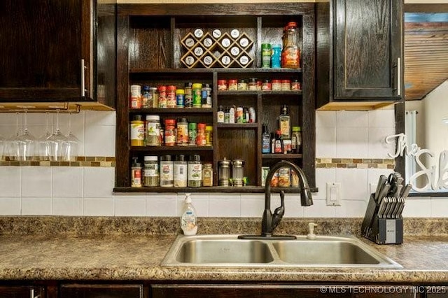 bar with sink, dark brown cabinets, and backsplash