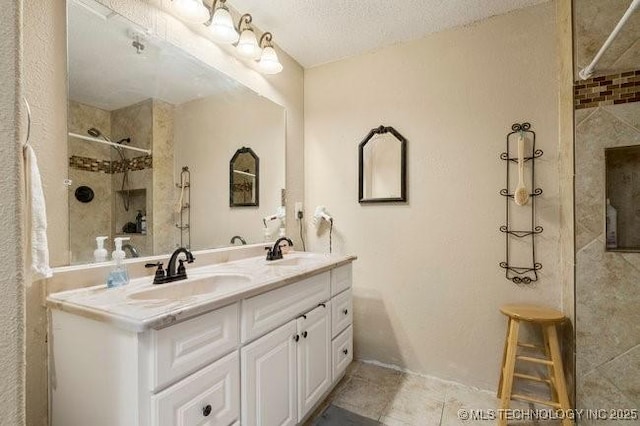 bathroom featuring a tile shower, vanity, and a textured ceiling