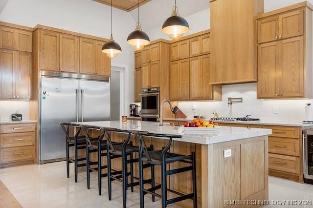 kitchen featuring a kitchen island with sink, hanging light fixtures, stainless steel appliances, and a kitchen bar