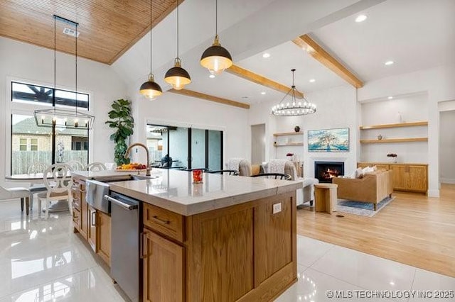 kitchen with an inviting chandelier, decorative light fixtures, dishwasher, an island with sink, and beam ceiling