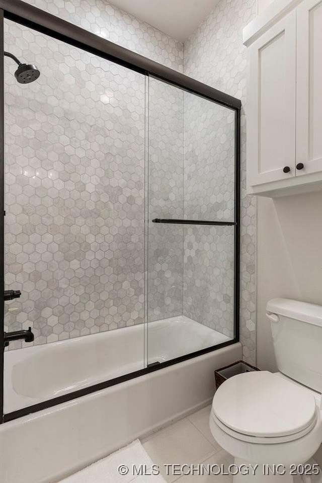 bathroom featuring tile patterned flooring, enclosed tub / shower combo, and toilet