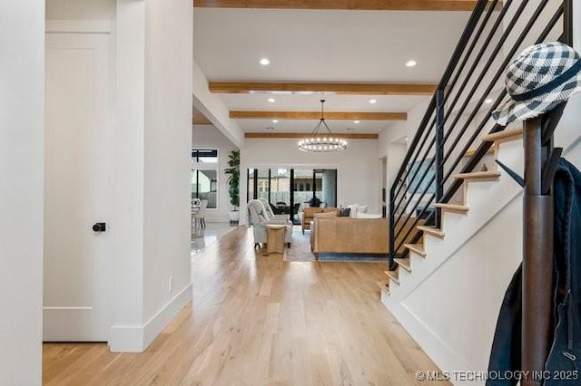 foyer entrance with beamed ceiling, an inviting chandelier, and light hardwood / wood-style flooring