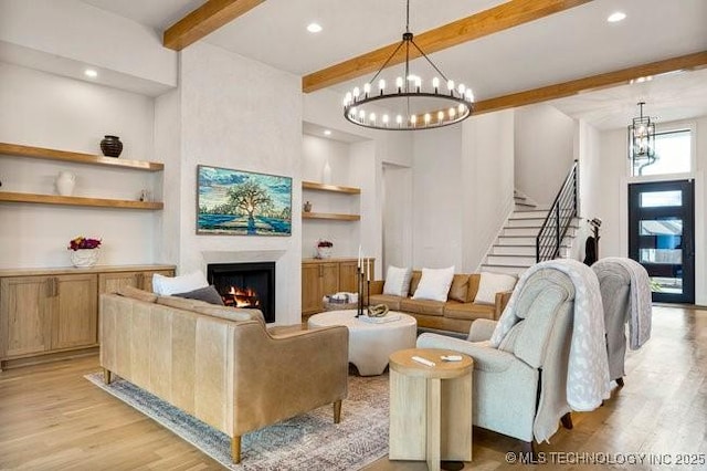 living room featuring an inviting chandelier, beam ceiling, built in features, and light wood-type flooring