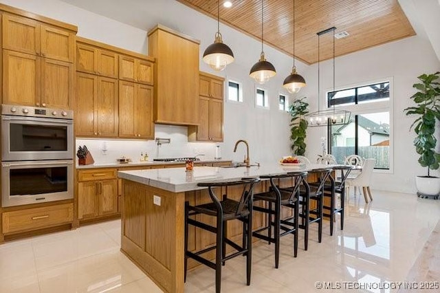 kitchen featuring wood ceiling, a kitchen breakfast bar, pendant lighting, stainless steel appliances, and a kitchen island with sink