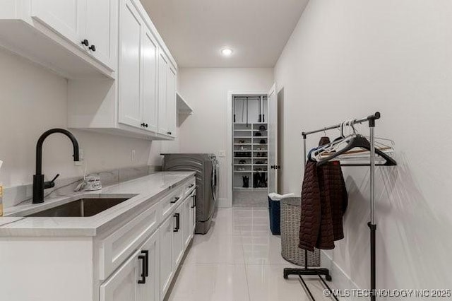 washroom featuring cabinets, washing machine and clothes dryer, sink, and light tile patterned floors