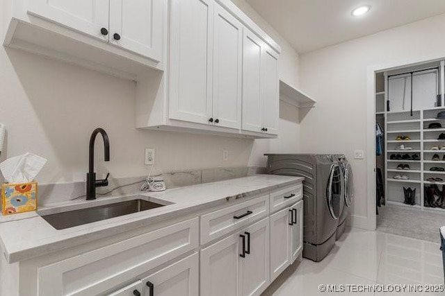 laundry room featuring cabinets, washing machine and clothes dryer, sink, and light tile patterned floors