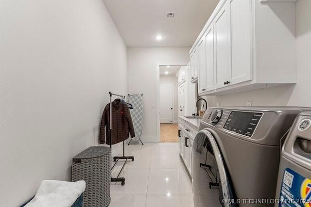 clothes washing area featuring cabinets, light tile patterned flooring, separate washer and dryer, and sink