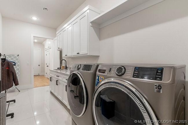 washroom with cabinets, washing machine and dryer, sink, and light tile patterned flooring